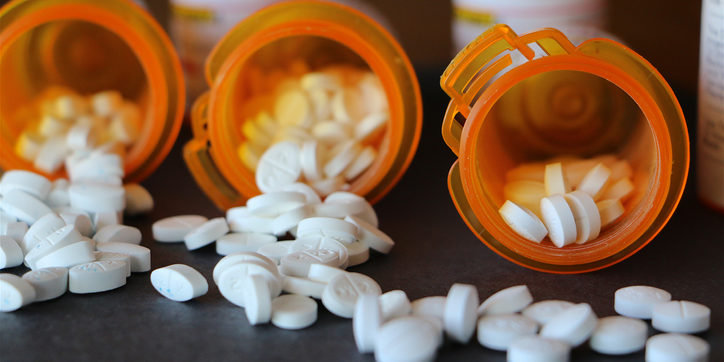 White tablets spilling out of medication bottles, addiction concept.