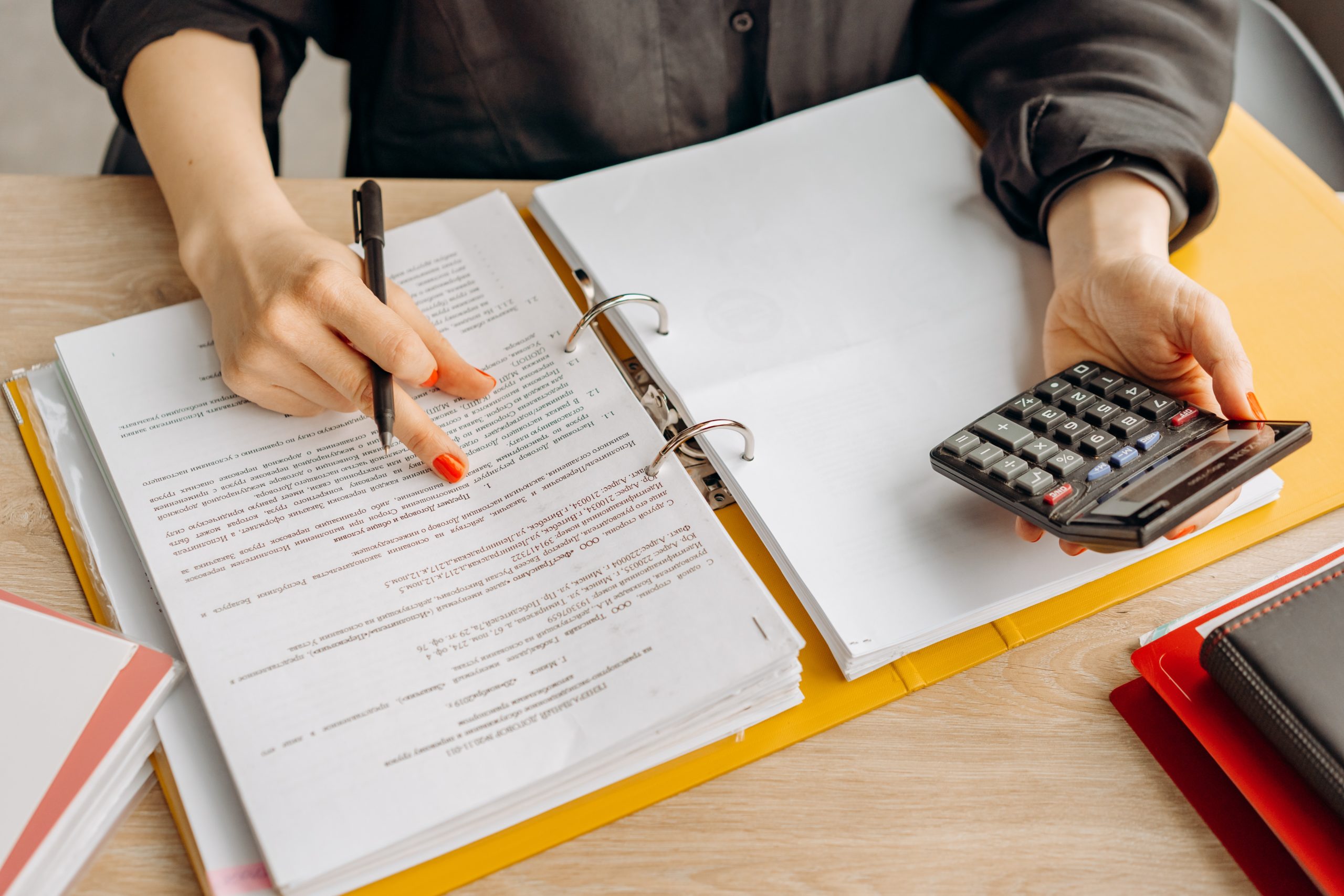 closeup of an open binder and person holding a calculator