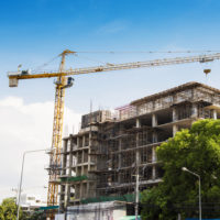 Hospital building under construction with cranes against a blue sky.