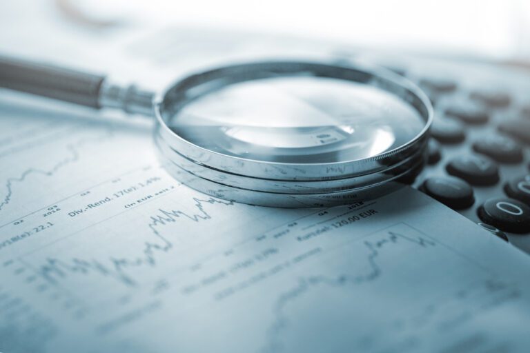 Magnifying glass, calculator and charts on paper